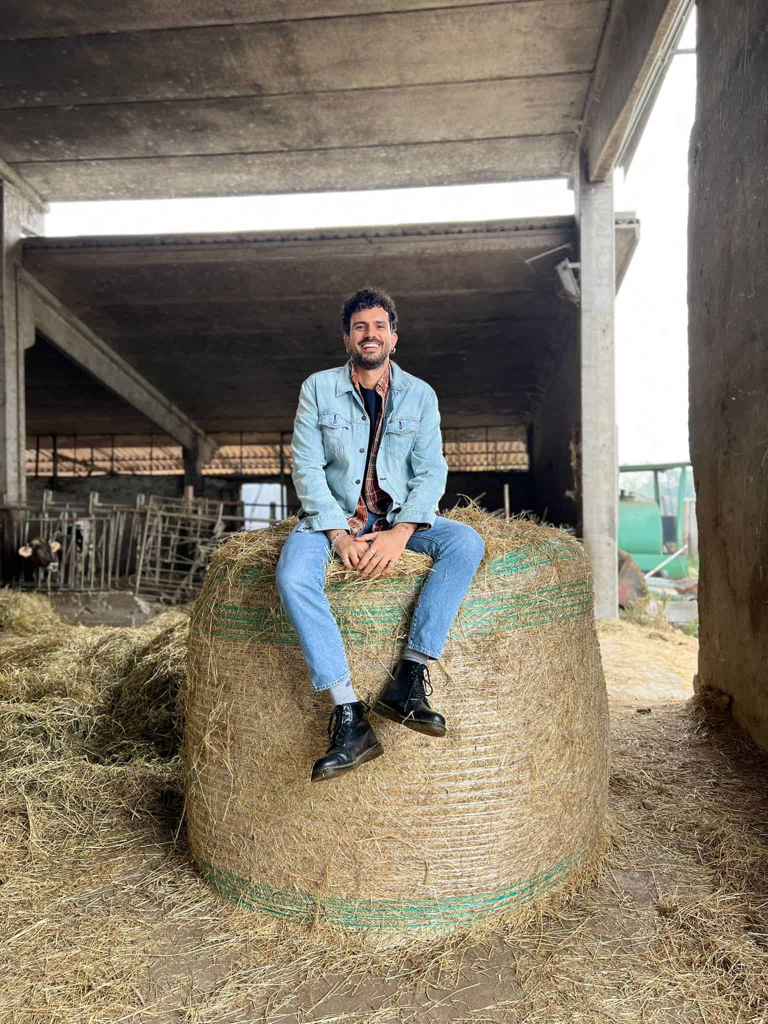 Marco Bianchi seduto su un ballone di fieno in fattoria