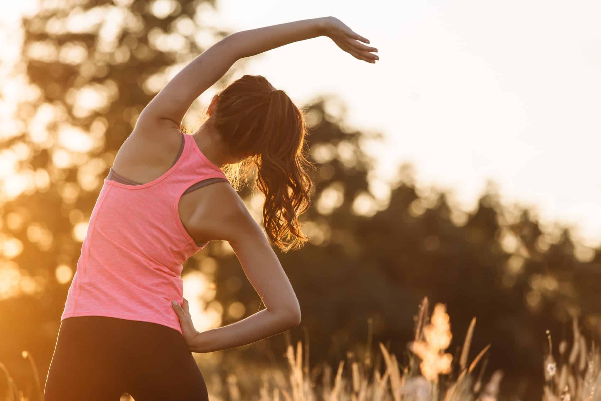 ragazza che fa stretching al parco di spalle