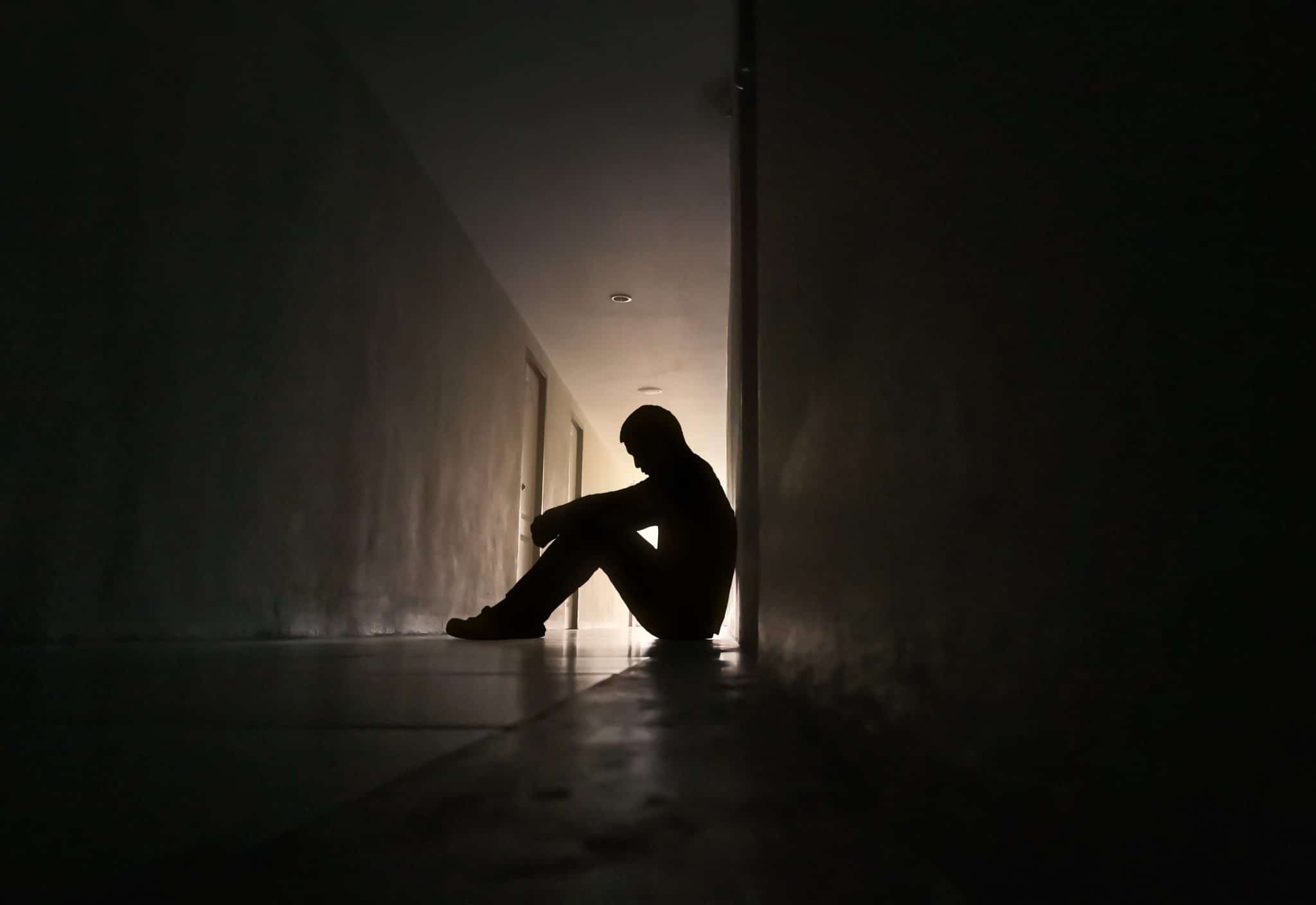 persona depressa seduta in un corridoio al buio
