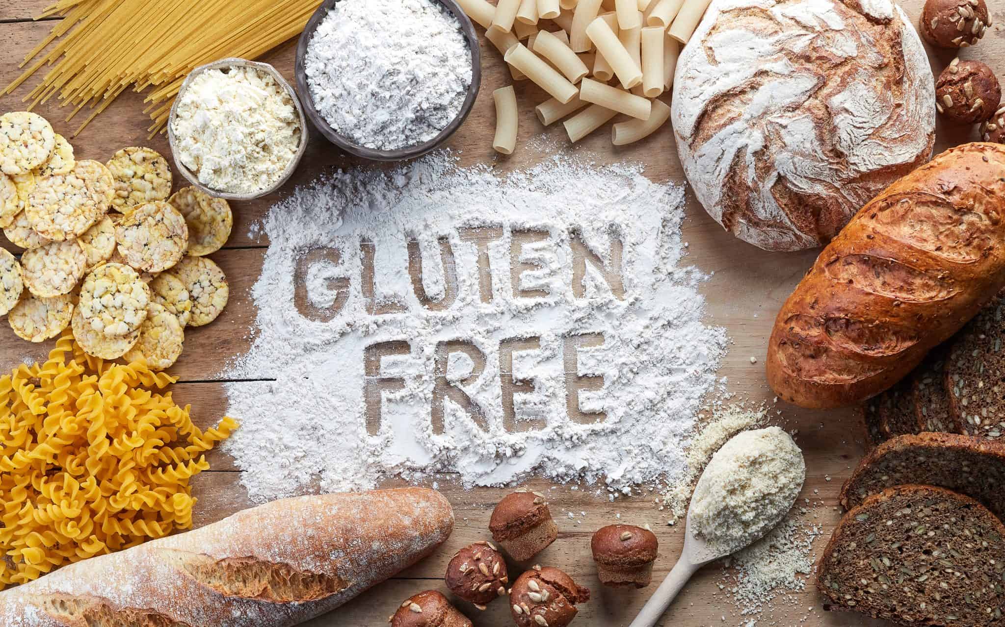 alimenti che contegono glutine sul tavolo e scritta con la farina "gluten free"